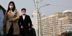 Des personnes portent des masques de protection dans une rue de pekin lors de la pandemie liee au coronavirus (covid-19) en chine
