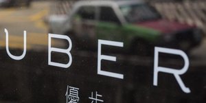 Logo Uber avec un taxi en arrière plan, à Hong Kong en Chine en août 2015 (VTC)