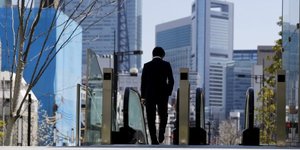Un salarié japonais marche seul devant un escalator