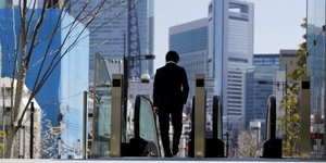 Un salari japonais marche seul devant un escalator