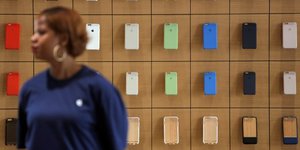 Une employe d'un Apple Store se tient devant un rayon d'iPhone  New York en juillet 2016